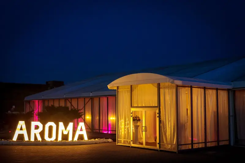 Inscripția AROMA iluminată la intrarea în salon
